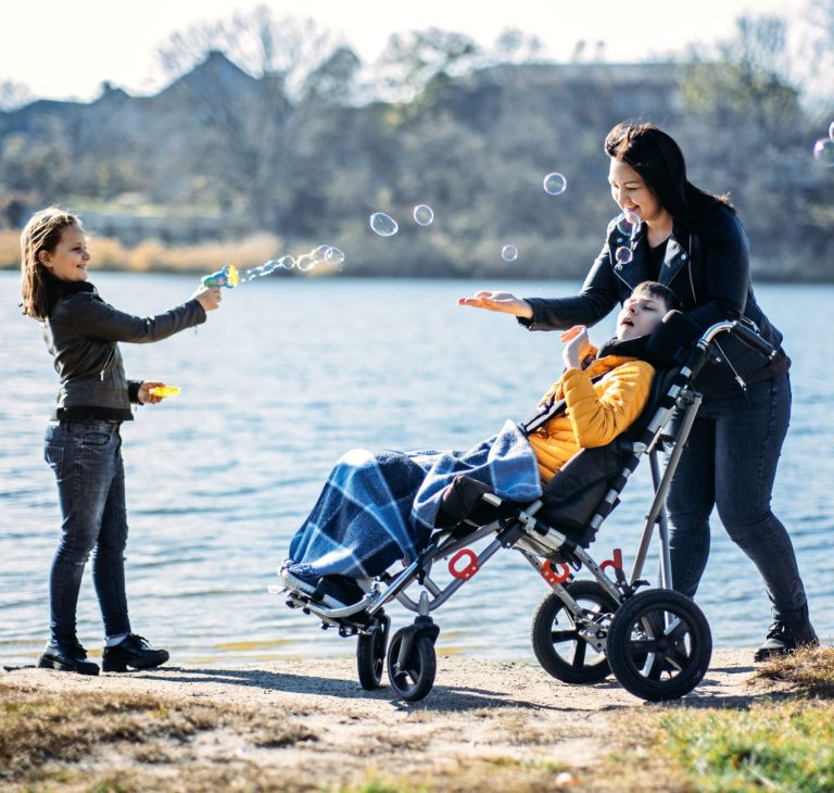 Happy family, mother, daughter and son with cerebral palsy spending time together on the river bank. Portsmouth PBS Network.